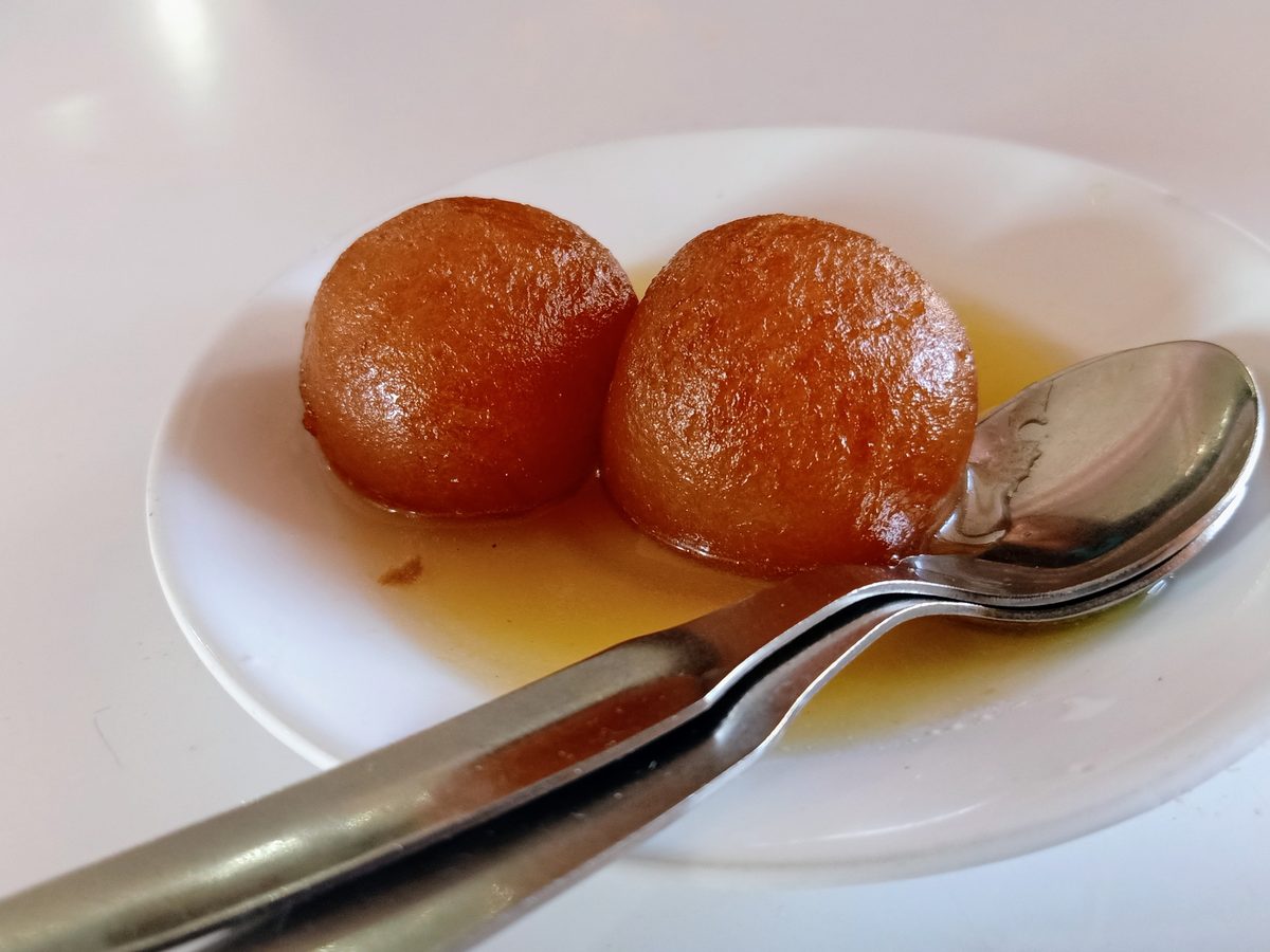 Two gulab jamun in syrup on a plate